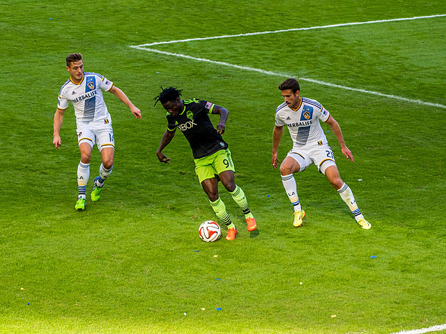Obafemi Martins dribbling between two L.A. Galaxy defenders, 2014