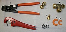 Tools and fittings used in a plumbing installation with PEX piping. (1) crimping tool to squeeze a metal band to join a pipe and a fitting (2) compression coupling joining two 1/2 inch pipes (copper or PEX) (3) "T-joint" to connect 3/4", 3/4", and 1/2" pipes (4) Copper-to-PEX 1/2" connection (requires soldering) (5 and 6) tools to undo PEX connections (7) crimp rings to squeeze metal band to connect PEX to a fixture (8) PEX tube cutter. PEX installation tools and fittings.jpg