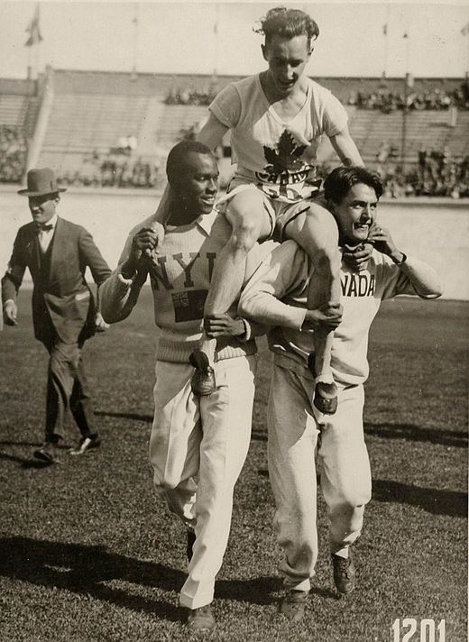 Percy Williams, die gedragen wordt door Phil Edwards (links) en een ander lid van het Canadese estafetteteam op de Olympische Spelen van 1928.