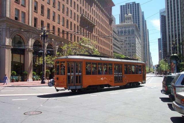 An F Market streetcar turns at the eastern end of Market Street, in front of the Ferry Building.