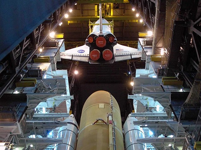 A crane moves Discovery toward the external tank and SRBs in high bay 3 of the Vehicle Assembly Building for STS-124.