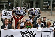 Gruppe von Aktivisten hält Plakate mit Aufschrift: "Who made my clothes?"