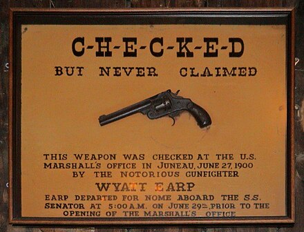 Said to be Wyatt Earp's pistol, left behind in Juneau, Alaska, but Earp was arrested in Nome three days before the date on the sign.