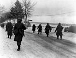 Troops of the 101st Airborne move out of Bastogne, after having been besieged there for ten days, 31 December 1944. 101st Airborne troops move out of Bastogne.jpg