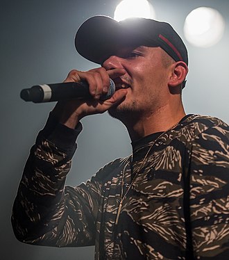Capital Bra during a concert as part of his "Blyat" Tour in the Hirsch, Nuremberg, Germany in February 2018 2018 Capital Bra (cropped).jpg