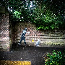 A mural by Hendog of a policeman seemingly chasing and pointing to a teddy bear holding bottles of alcohol.