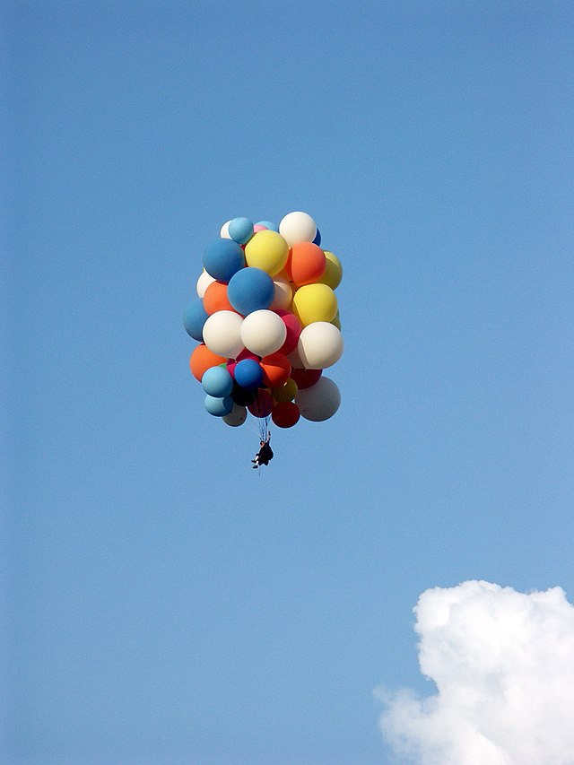 man attaches balloons to mother in lawn chair