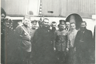 A grainy black and white photograph of a dozen men, most wearing military uniforms