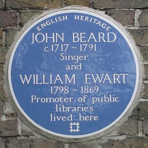 A Blue plaque on a brick wall with the words "John Beard C1717 – 1791 Singer and William Ewart 1798 – 1861 Promoter of Public Libraries