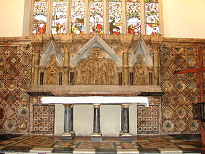 Un retablo de mármol debajo de una vidriera, con tres escenas de la Crucifixión;  un altar de granito con seis pilares