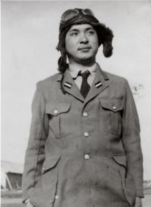 Photo noir et blanc d'un homme en uniforme, portant un casque de pilote sur la tête.