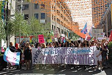 Een menigte mensen achter een spandoek met de tekst 'Mars voor rechten van transmigranten'