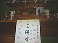A wooden household shrine featuring two tōrō lanterns made of wood, and a piece of paper announcing the name of a baby.