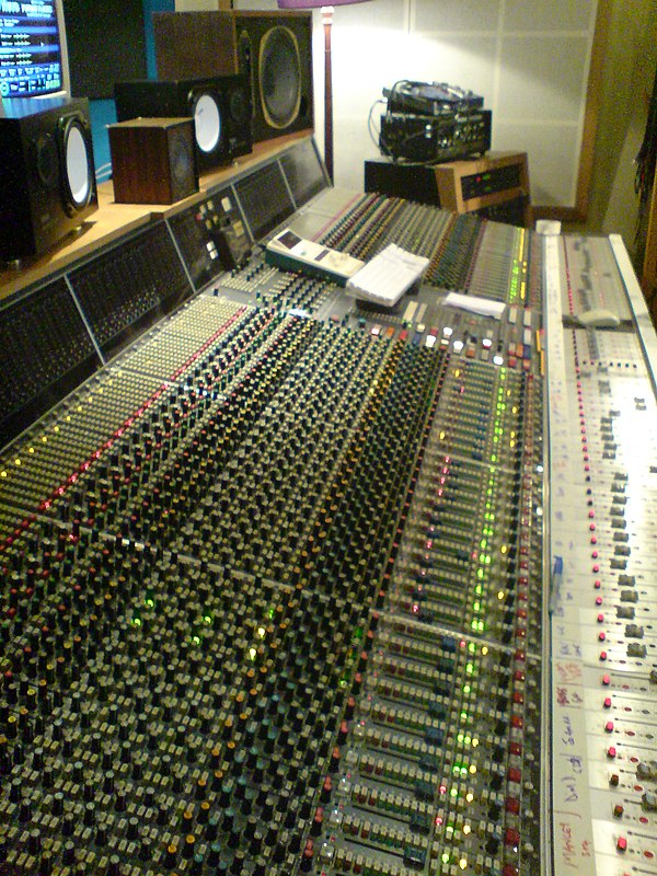 Neve VR60, a multitrack mixing console. Above the console are a range of studio monitor speakers.