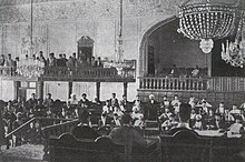 Large hall with two balconies, filled with men