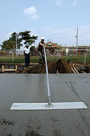 Smoothing concrete with a large concrete float, or bull float US Navy 030514-N-8726C-002 Chief Builder R. Brett James, a U.S. Navy Reservist, volunteers his time to level out a concrete foundation as part of a Navy Misawa Seabee project.jpg