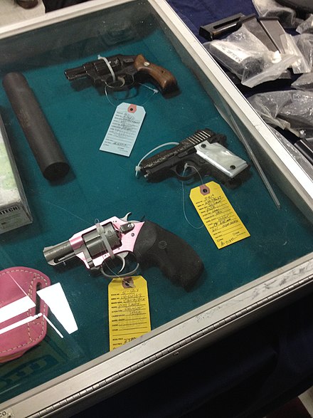 3 pistols and a silencer in a glass case