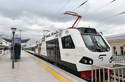 Электровоз AZ4A-0002 с пассажирским поездом производства Stadler на перроне вокзала