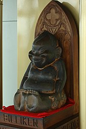 Wooden statue of the Billiken in Tsutenkaku tower Billiken side view.jpg