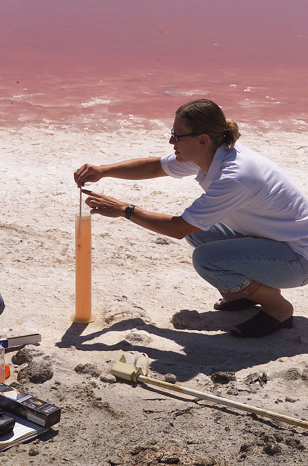 A NASA technician measures the concentration level of brine using a hydrometer at a salt evaporation pond in San Francisco.