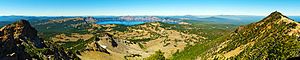 Una foto panoramica mostra Crater Lake sullo sfondo centrale, con le montagne in primo piano a sinistra e a destra