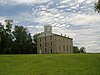 Three story gray rectangular building on a grassy hill