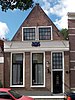 Huis met topgevel, gepleisterd, met gevelsteen