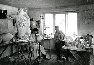A photograph of Josef Ekberg (left) and Gunnar Wennerberg (right), seated and painting vases in the Gustavsberg Porcelain Factory, around 1900.