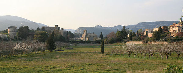 Vu par le sud, le moulin, le château, les églises et le vieux village avec en fond, petit et grand Luberon séparés par la combe de Lourmarin.