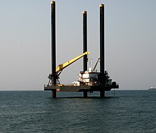 An offshore oil drilling platform off the coast of central Angola Offshore platform on move to final destination, Ilha de Luanda (cropped).JPG