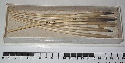 Picture of a box of writing quills with barbs removed. Some have ink-stained tips from use.