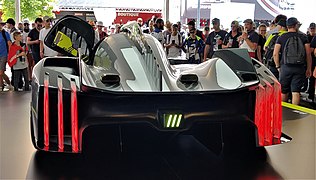 Photo de l'arrière d'une voiture de course grise et noire sur un stand d'exposition.