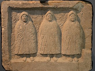 The Genii Cucullati found in a shrine in the vicus, early 3rd century AD, Housesteads Roman Fort (Vercovicium) Relief of the Genii Cucullati (hooded deities) found in a shrine in the vicus, early 3rd century AD, Housesteads Roman Fort (Vercovicium) (44588550041).jpg