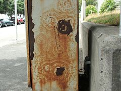 Concentric rust patterns breaking through a painted surface