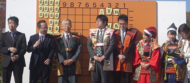 Professional shogi players at a human shogi [ja] exhibition match in Himeji, Japan in 2018. From left to right: Toshiaki Kubo, Keita Inoue, Masakazu W