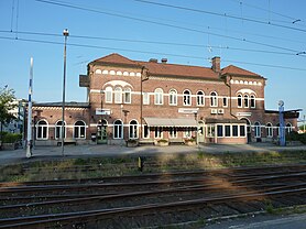 Brown brick railway station with tracks in front. The sign reads "Värnamo".