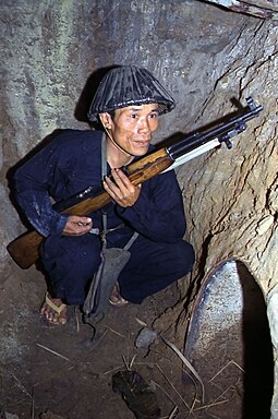 Viet Cong soldier crouches in a bunker with an SKS rifle Vietcong1968.jpg