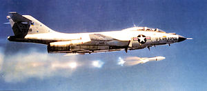 Black-and-white photo of jet aircraft flying right above clouds. On the aircraft's side is a symbol with a star, to the right of which says U.S. Air Force. Its horizontal stabilizers are located atop its fin.