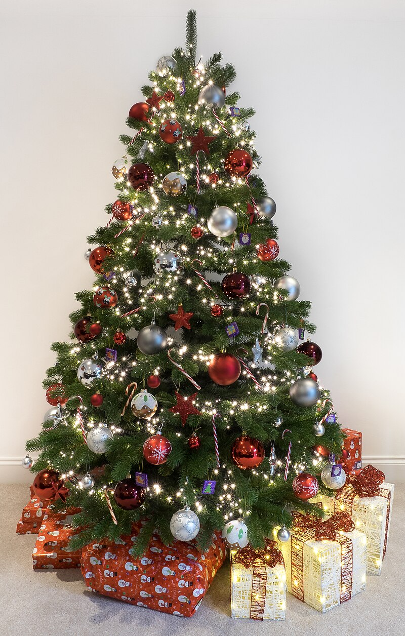 Christmas tree decorated with lights, stars and glass balls. Wrapped presents are under tree