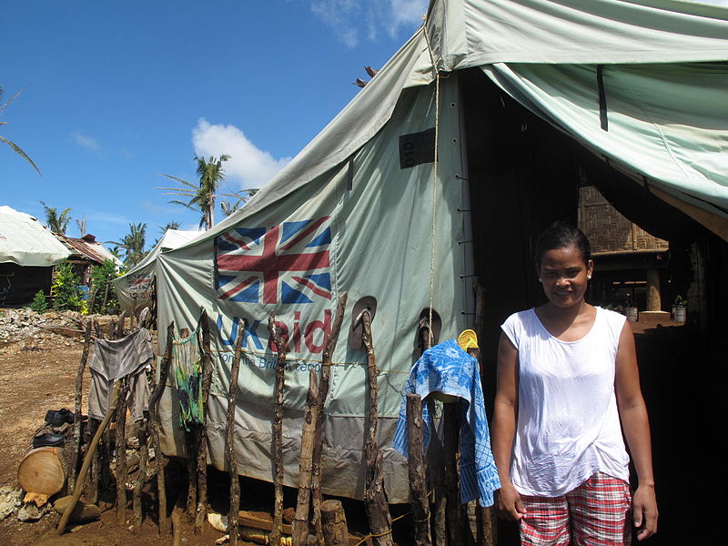 File:A woman stands in front of a tent supplied by UK aid near Guiuan in the Philippines (14133457721).jpg