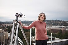 woman with telescope standing on top of building