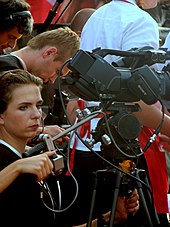 photographie : une femme dans une foule tient une caméra