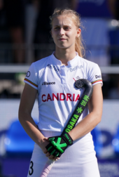 Rasir trägt weiße Spielkleidung, auf den Ärmeln ist die belgische Flagge erkennbar. Vor dem Körper hält sie das schwarze Unterteil ihres Schlägers.