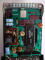 O interior de uma calculadora científica Casio fx-20 de meados da década de 1970, usando um VFD.  O circuito integrado do processador (IC) é feito pela NEC.  Componentes eletrônicos discretos como capacitores e resistores e o IC são montados em uma placa de circuito impresso (PCB).  Esta calculadora usa uma bateria como fonte de alimentação.