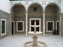 Patio du Petit Palais avec une fontaine de marbre au milieu de la cour et une colonnade.