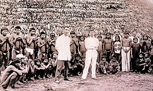 Employees of Julio César Arana stand in front of their enslaved indigenous workers. Photograph circa 1912.jpg