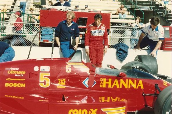 Pole-sitter Mario Andretti waits by his car during a practice session.