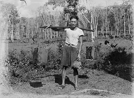 Samoan man carrying two containers over his shoulder