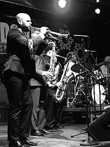 Guy playing trumpet in black and white.