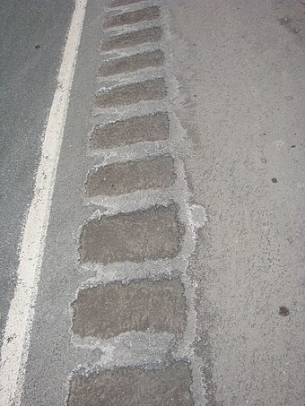Traction sand filled shoulder rumble strip. The sand is "cemented" in-place and is not easily removed by truck traffic.